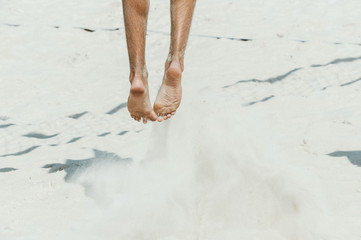 Close-up of feet and legs of a male beach volleyball player