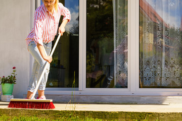 Woman using broom to clean up backyard patio