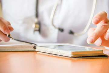 Young female doctor using modern smartphone in the hospital, seeking information in the internet. Close up