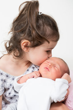 children sister kissing his little brother newborn baby with love