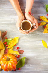 Hands of a girl holding hot coffee on a gray wooden background with copy space. Top view