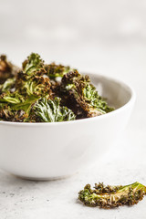 Kale chips in a white bowl on white background. Clean eating concept.