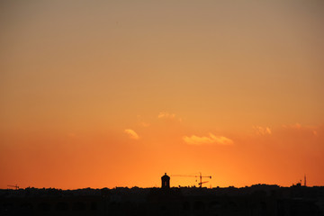 Orange sunset sky above silhouette of city towers