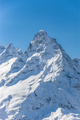 Fototapeta na wymiar Mt. Belalakaya summit against clear blue sky in winter sunny day. Dombay ski resort, Western Caucasus, Russia.