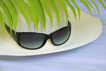 Straw hat and sunglasses. On a wooden background.