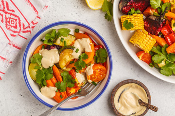 Salad with baked vegetables with tahini in white plate, white background, top view. Clean eating concept.