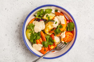 Salad with baked vegetables with tahini in white plate, white background, top view. Clean eating concept.