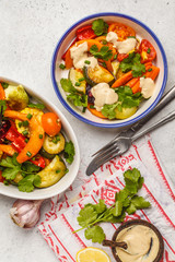 Salad with baked vegetables with tahini in white plate, white background, top view. Clean eating concept.