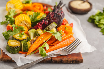 Baked vegetables: pumpkin, beets, carrots, peppers, zucchini and corn on wooden board.
