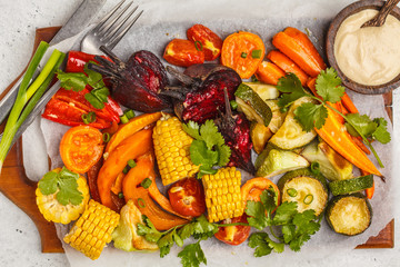 Baked vegetables: pumpkin, beets, carrots, peppers, zucchini and corn on wooden board.