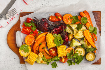 Baked vegetables: pumpkin, beets, carrots, peppers, zucchini and corn on wooden board.