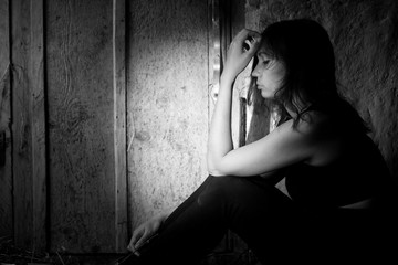Teenager girl with depression alone in the dark room. Black and white photo