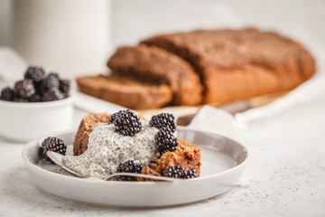 Chocolate vegan banana bread with chia pudding and blackberries, white background.