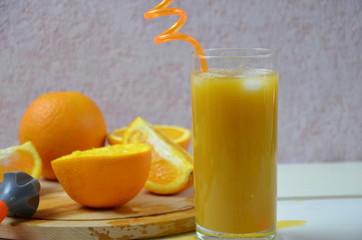 glass of fresh orange juice with fresh fruits on white table.