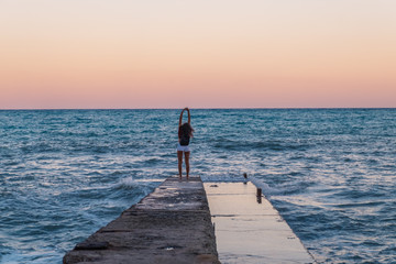 Relaxed young woman on a pier on the background of the sea