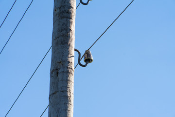 Photograph of a wooden pole for electricity on the sky background.