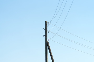 Photograph of a wooden pole for electricity on the sky background.