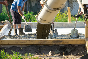 Pouring concrete from a concrete mixer. The work of people pouring concrete.