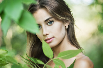 Portrait of young gorgeous lady with green lives, close up, shallow depth of field. Shot through leaves