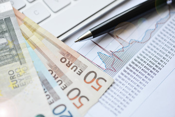 Analyzing investment or business charts with computer keyboard and euro banknotes
