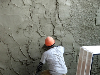 Construction workers plastering wall using cement plaster at the construction site. They are...