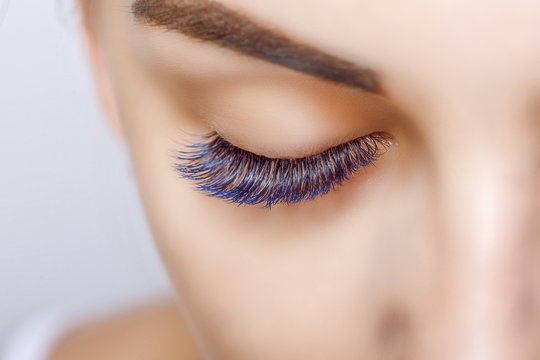 Eyelash Extension Procedure. Woman Eye with Long Blue Eyelashes. Ombre effect. Close up, selective focus.
