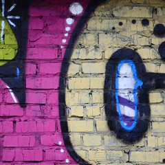 Fragment of graffiti drawings. The old wall decorated with paint stains in the style of street art culture. Colored background texture