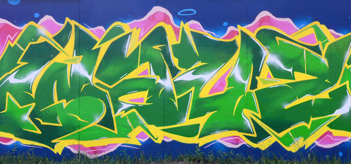 Full and acomplished graffiti artwork. The old wall decorated with paint stains in the style of street art culture. Colored background texture