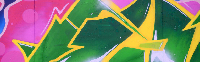 Fragment of graffiti drawings. The old wall decorated with paint stains in the style of street art culture. Colored background texture