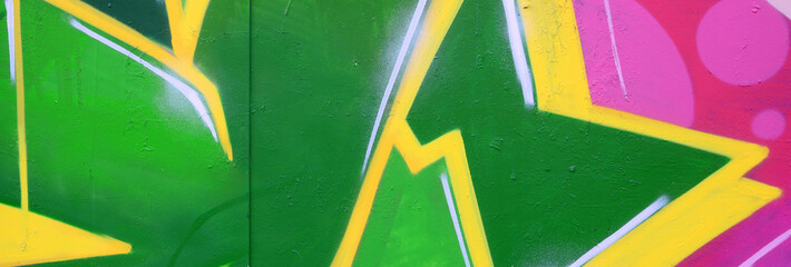Fragment of graffiti drawings. The old wall decorated with paint stains in the style of street art culture. Colored background texture