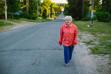 Elderly woman walking down the street in the village.