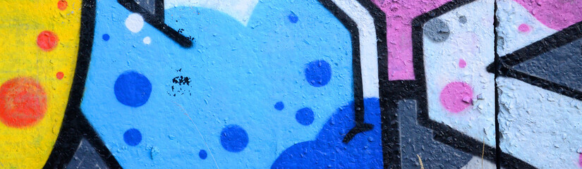 Fragment of graffiti drawings. The old wall decorated with paint stains in the style of street art culture. Colored background texture