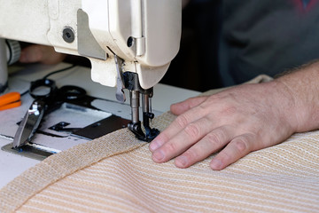 Men's hands sew bags on the sewing machine. Sewing bags for rice and sugar. Hired labor. Professional seamstress. Man seamstress. Men's hands behind sewing leather.