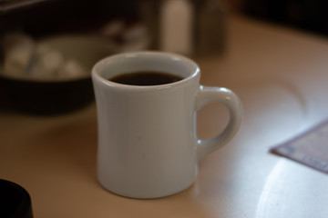 Coffee In A Mug On A Table With Cream In A Booth At A DIner During The Day