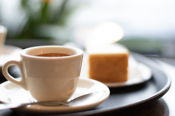 Espresso Macchiato at an italian breakfast bar in a cup on a saucer with a spoon with cheesecake.