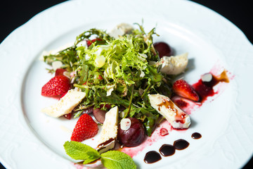 Strawberry tomato salad with feta cheese, olive oil on black background