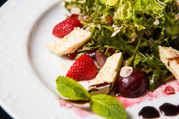 Strawberry tomato salad with feta cheese, olive oil on black background