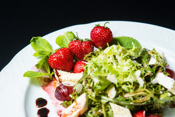 Strawberry tomato salad with feta cheese, olive oil on black background