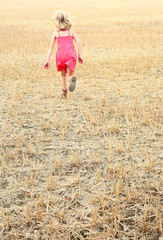 Naklejka na ściany i meble girl running across a cut corn field