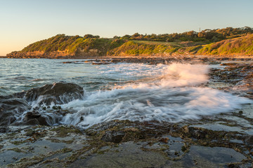 Waves splashing on a rocky beach at sunrise