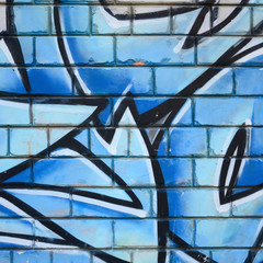 Fragment of graffiti drawings. The old wall decorated with paint stains in the style of street art culture. Colored background texture
