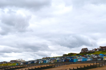 View of the sandy beach and painted wooden beach huts at Whitstable in Kent in south east England....