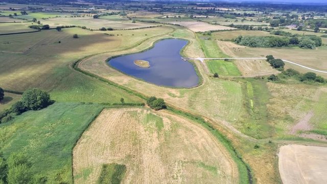 Aerial view, fly forward move. Drone panorama of plains and small pond hidden between fields