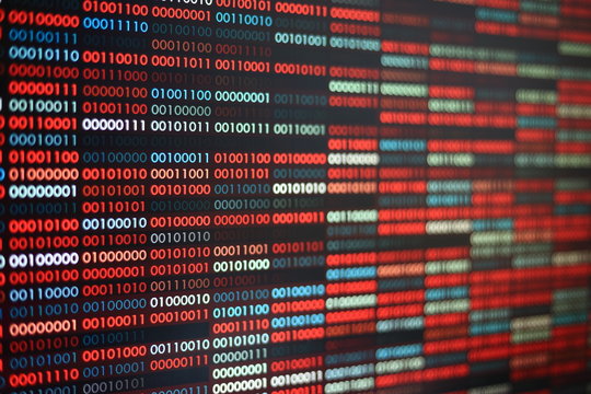 Computer virus infection. Row of binary codes randomly colored red and blue on black screen monitor background. Corrupted computer data bad sector hard disk visualization.