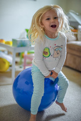 girl playing on bouncy ball and laughing