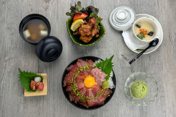 Top view of Maguro Don set with stream rice and fried chicken karaage, egg stream, soup and ice scream over the wooden table, luxury japanese food concept
