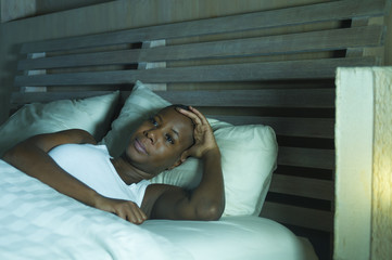 young sad and stressed black afro American woman lying on bed upset trying to sleep suffering...