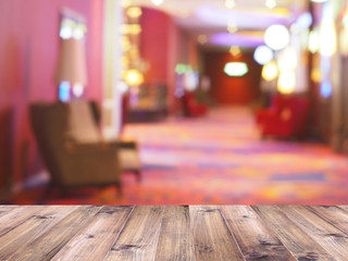 Wooden table top over abstract blur background of waiting room interior. Cinema, hotel or nightclub...