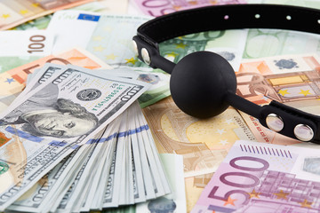 Black gag and heap of american dollars on euro banknotes