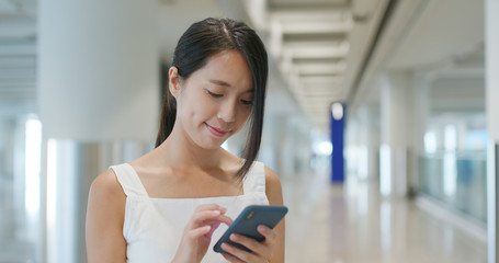 Woman holding cellphone with luggage in the airport